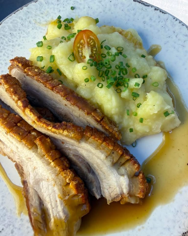Sliced roast pork with crackling, potatoes with chives and gravy