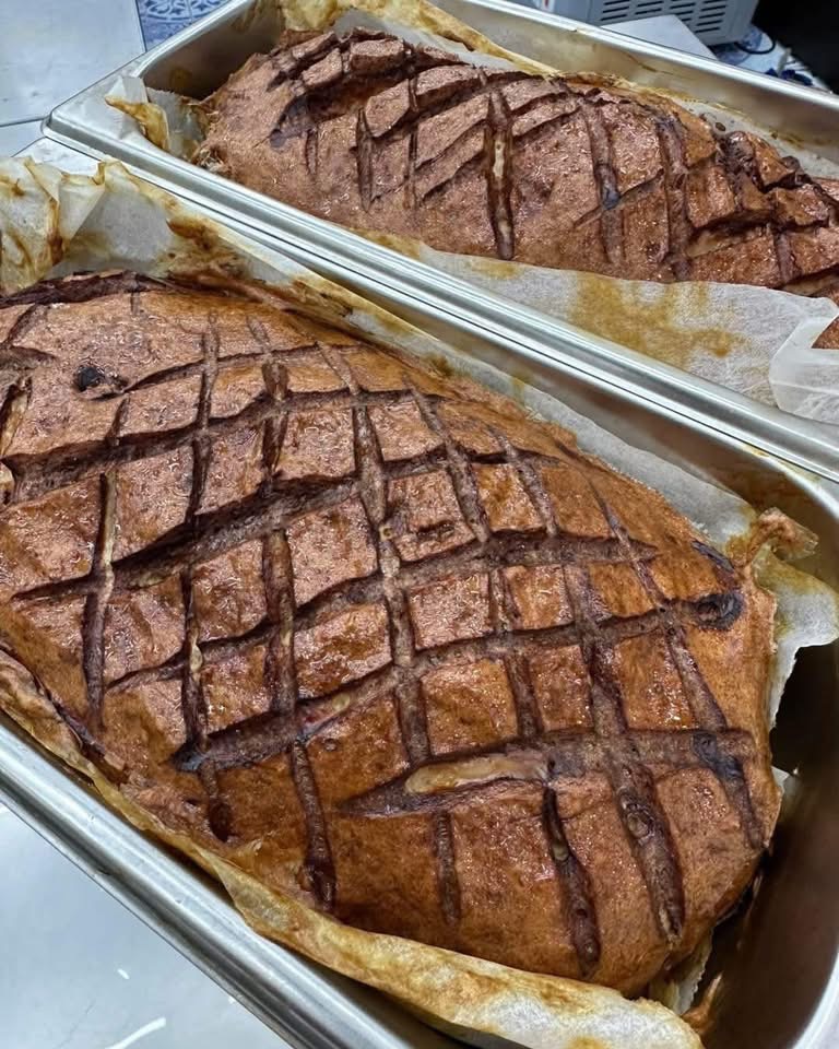 Whole oven-roasted pork with scored crackling in metal trays