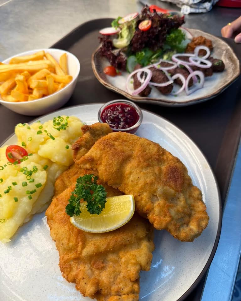 Golden schnitzel with potato salad, fries, lingonberry sauce and a side salad