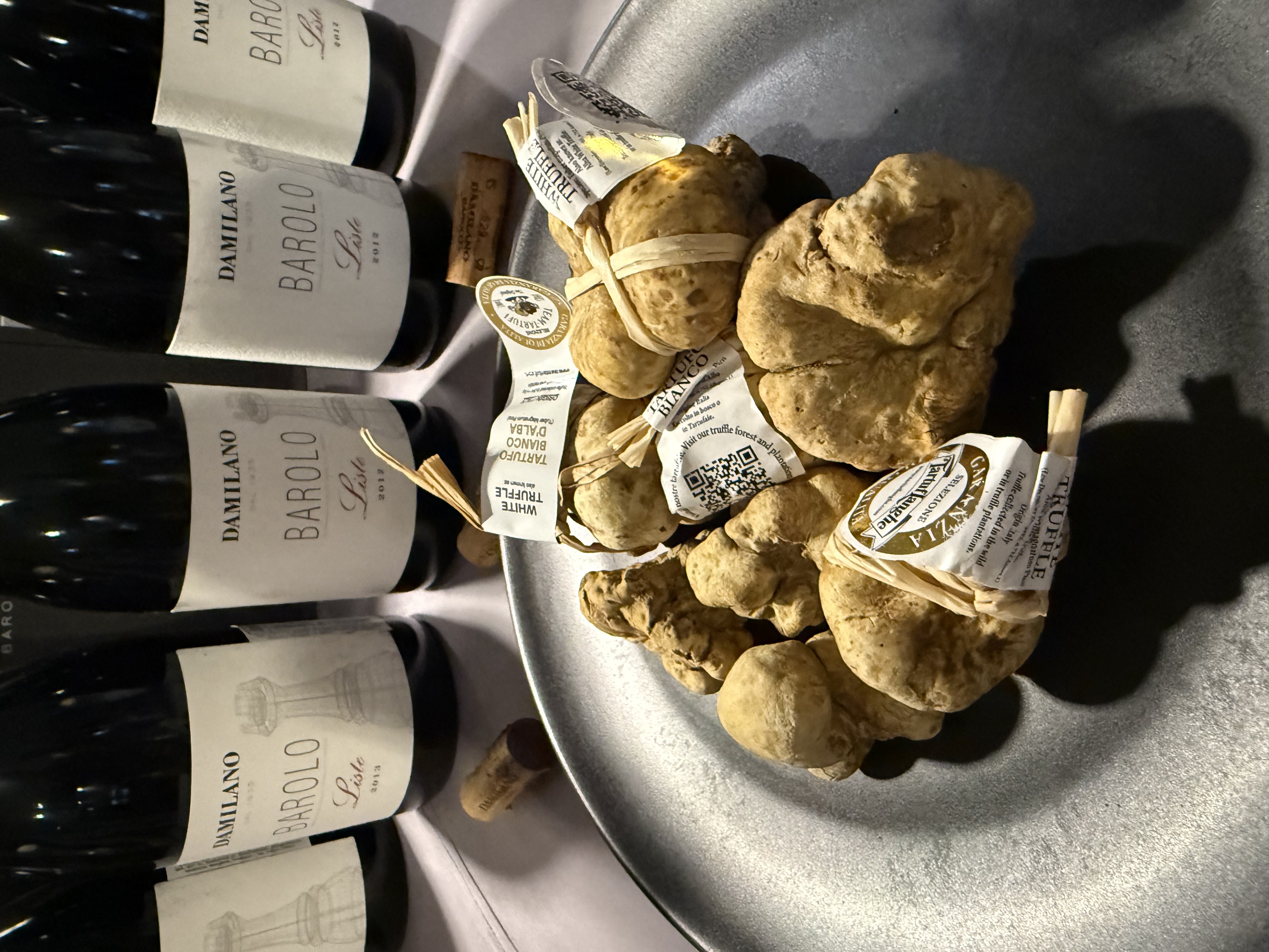 A certified Alba white truffle held in the hand, still wrapped with its quality seal